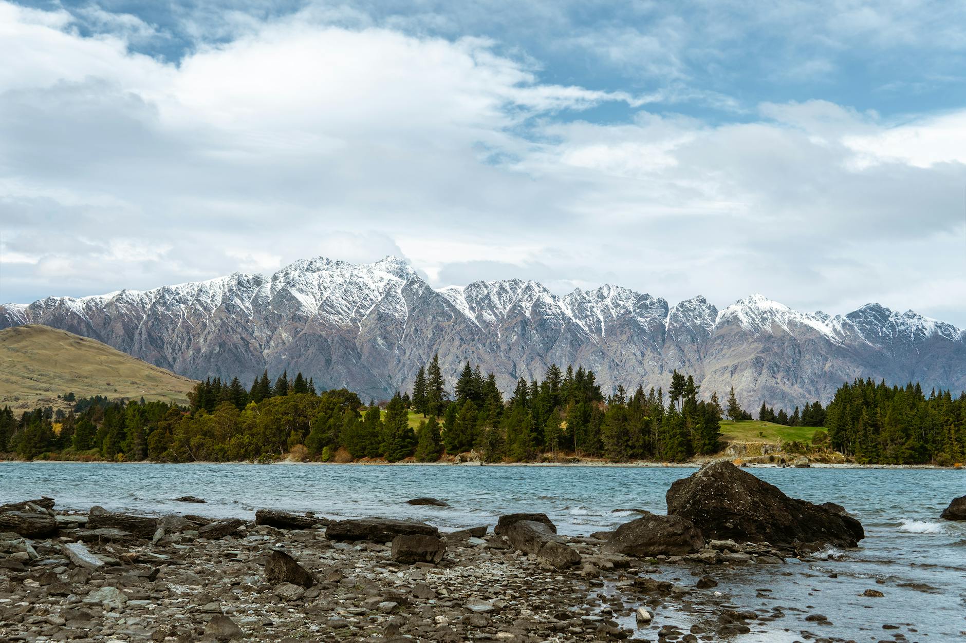 snowcapped mountain range seen from lake shore